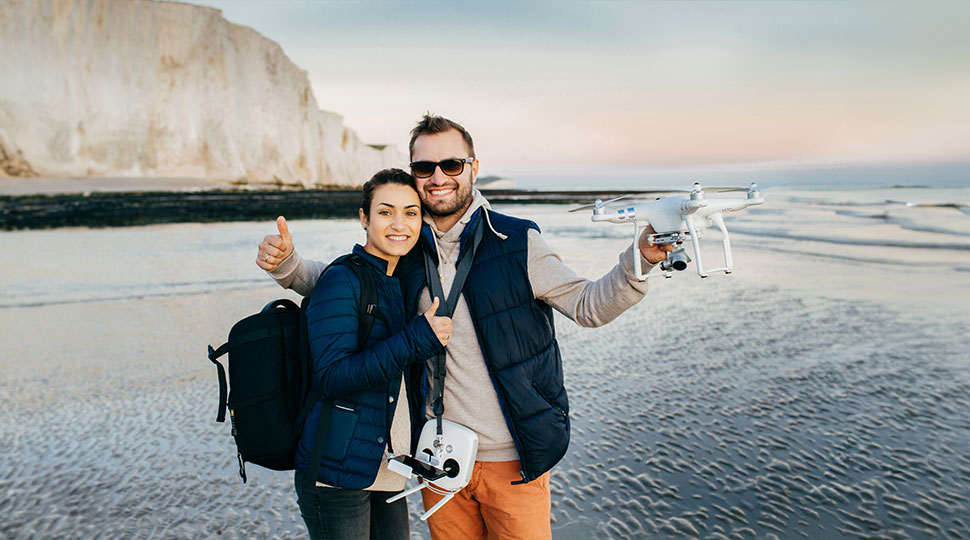 drone insurance for international travelers - happy couple posing with a drone - new to drones